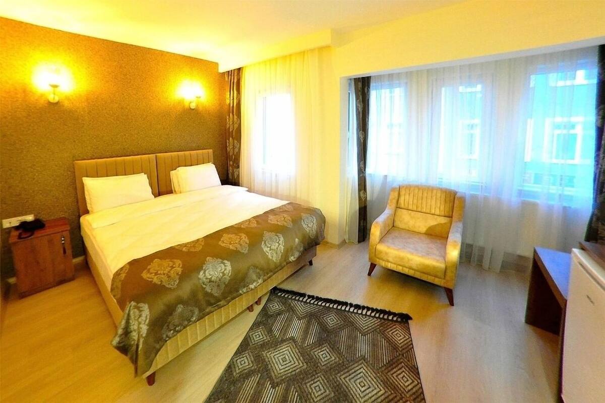 Een hotelkamer met een groot bed, een stoel, een bureau en een raam met gordijnen.