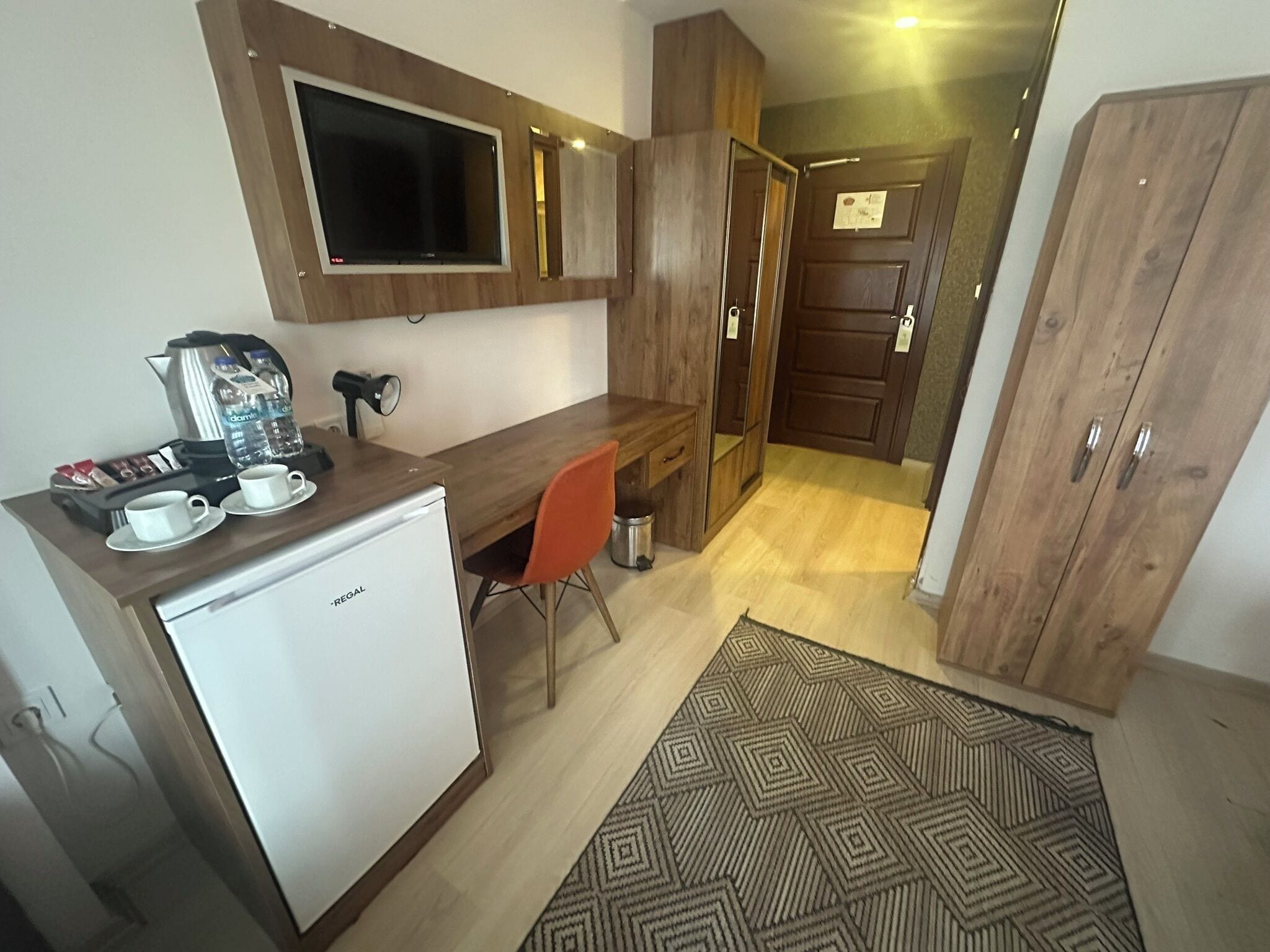 A compact kitchen with a refrigerator, a coffee machine, and a small dining table with two chairs.