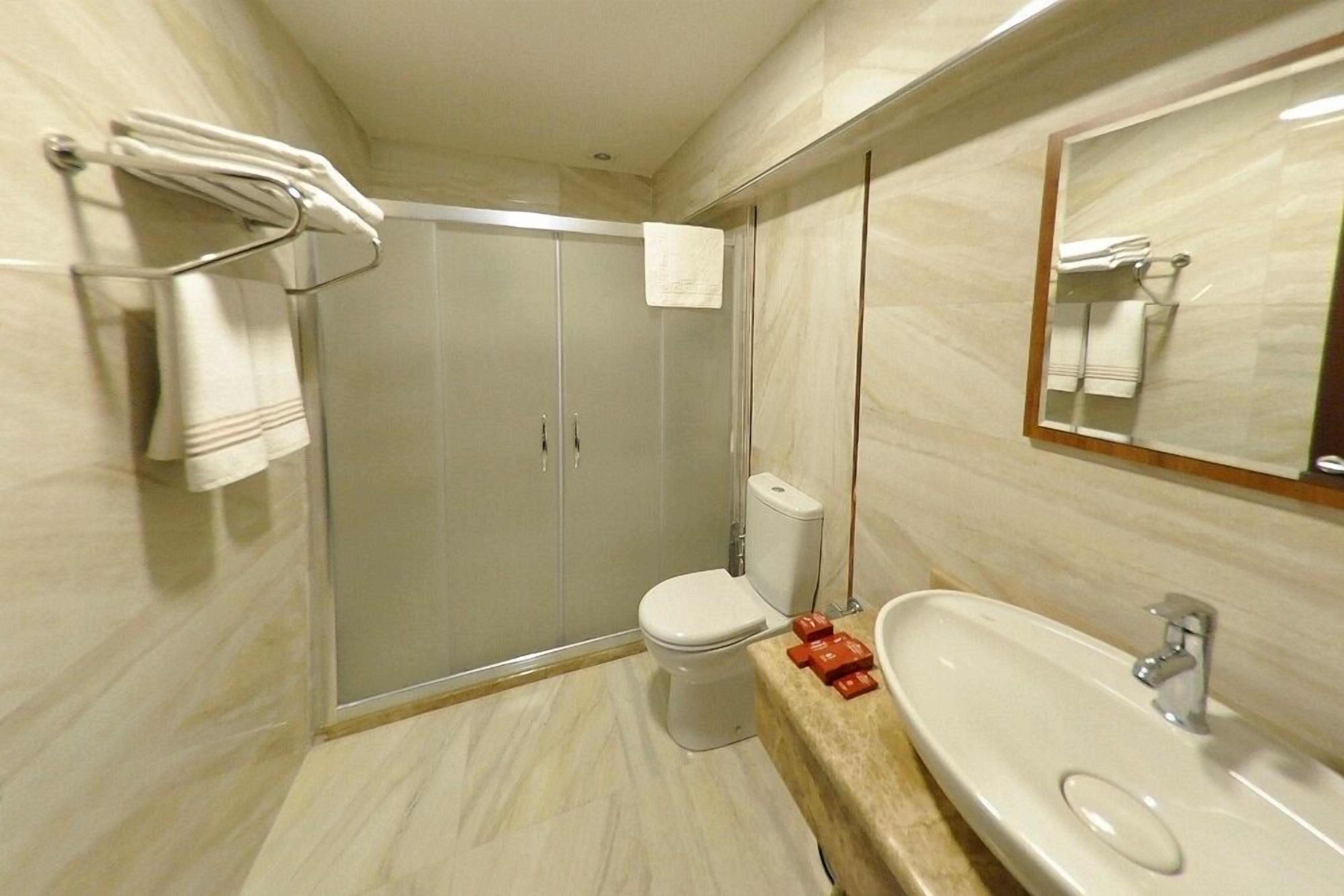Ein modernes Badezimmer mit einer Glasdusche, einer Toilette und einem Waschbecken mit Spiegel darüber.