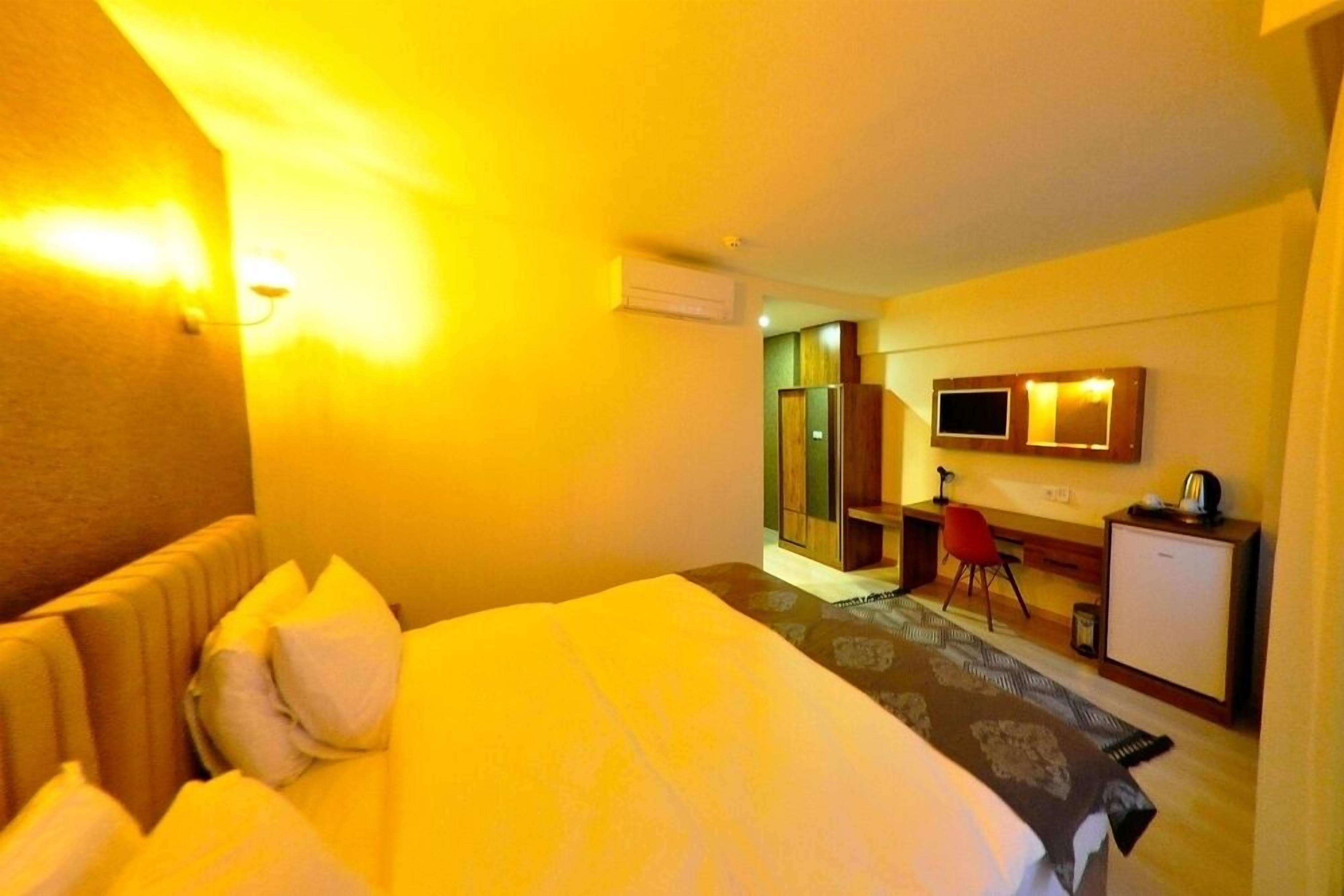 Een hotelkamer met een bed, een bureau, een stoel en een televisietoestel.