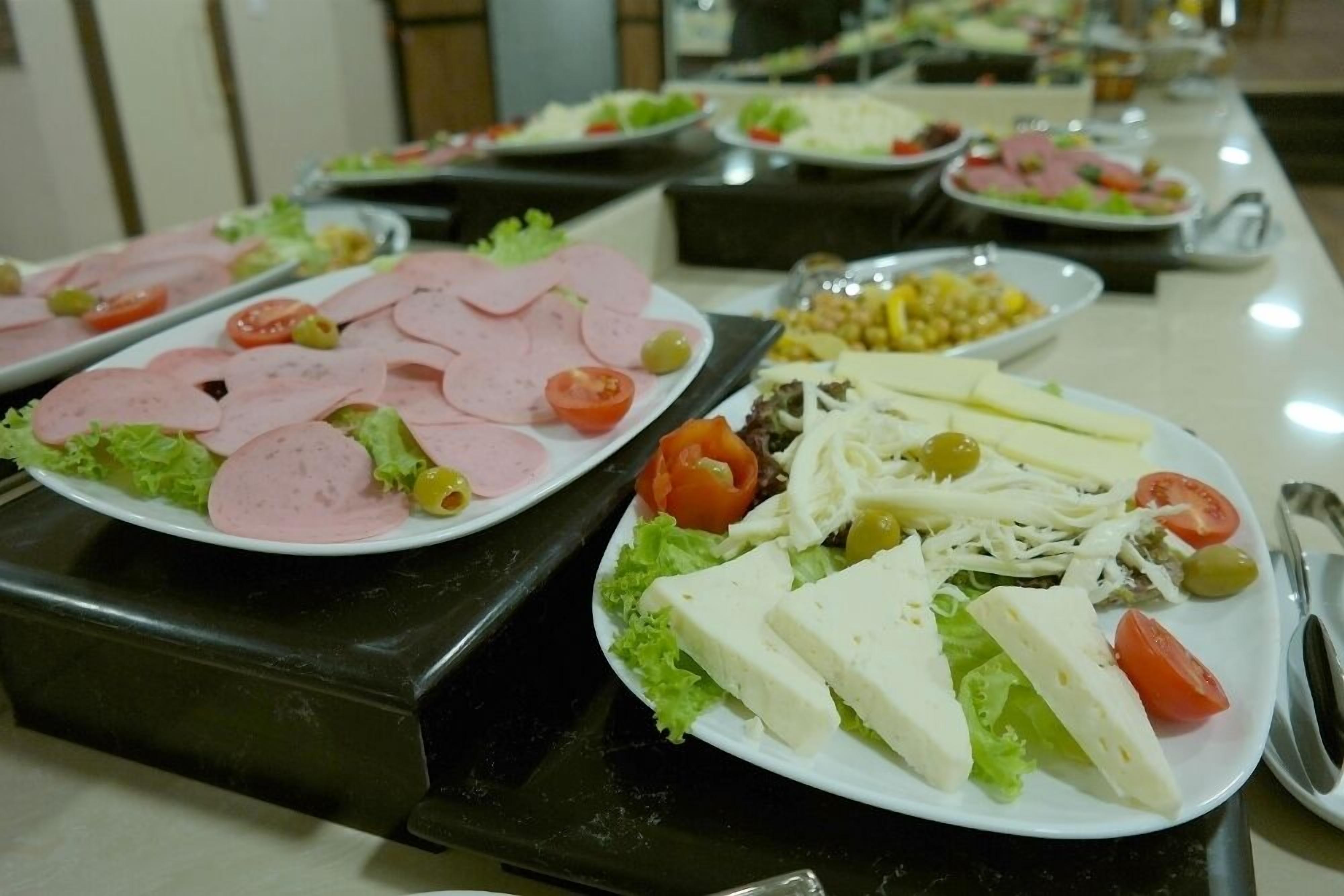 Un buffet con diverse portate, tra cui salumi, formaggi e insalate.