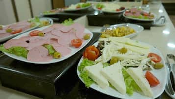 Un buffet proposant une variété de plats, notamment des viandes et des fromages en tranches, ainsi que des salades.