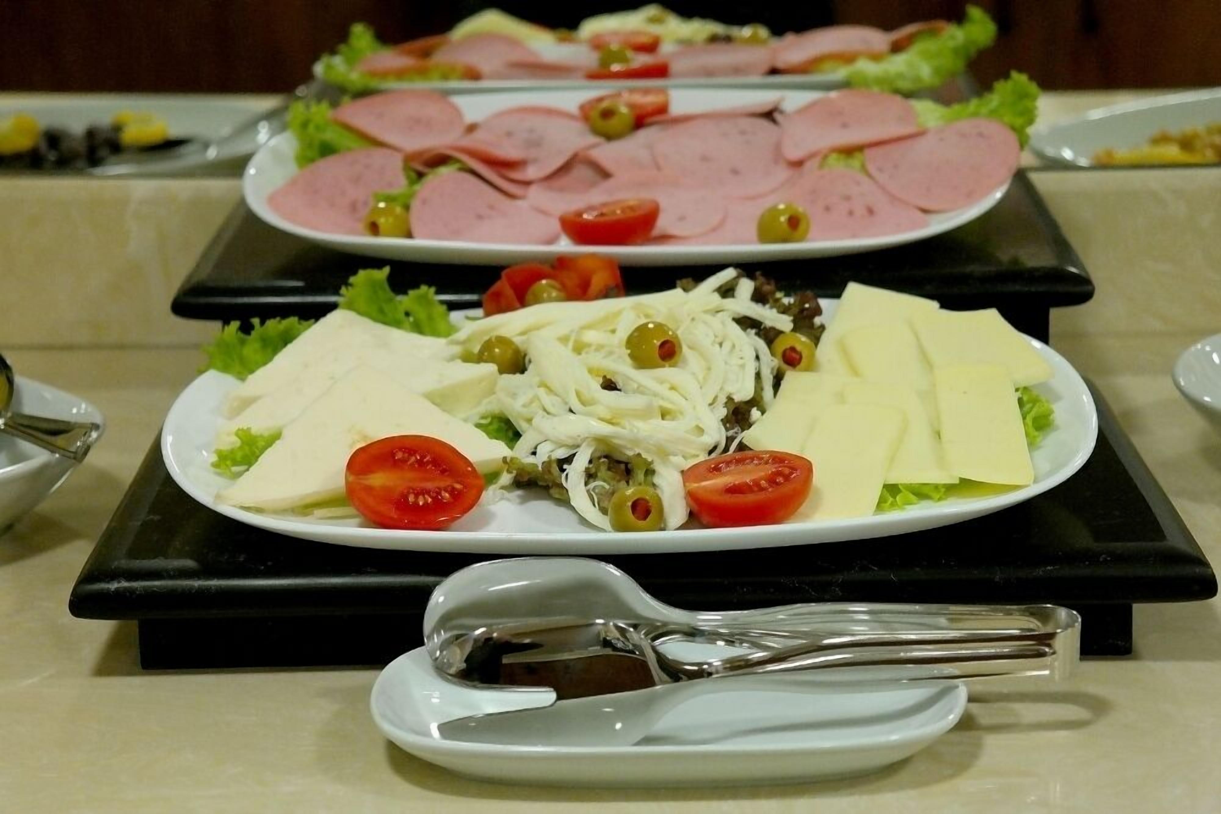 A buffet table with various food items including sliced meats, cheese, and vegetables.