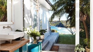 A bathroom with a white sink, wooden bench, and potted plants. - The Elysium by Contemporary Hotels (Palm Beach)