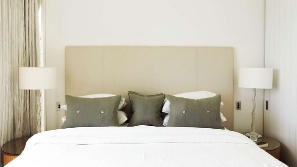 A hotel room with a large bed, two bedside lamps, and a curtain. - The Elysium by Contemporary Hotels (Palm Beach)