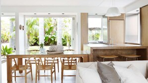 A modern kitchen with a large island, wooden chairs, and a dining table. - The Elysium by Contemporary Hotels (Palm Beach)