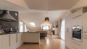 Une cuisine moderne dotée d’un îlot central, d’appareils électroménagers intégrés et d’une lucarne.