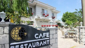 Une enseigne de café-restaurant avec un mur en pierre et un bâtiment en arrière-plan.