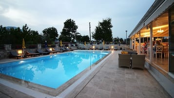 Una piscina al aire libre de temporada, sombrillas