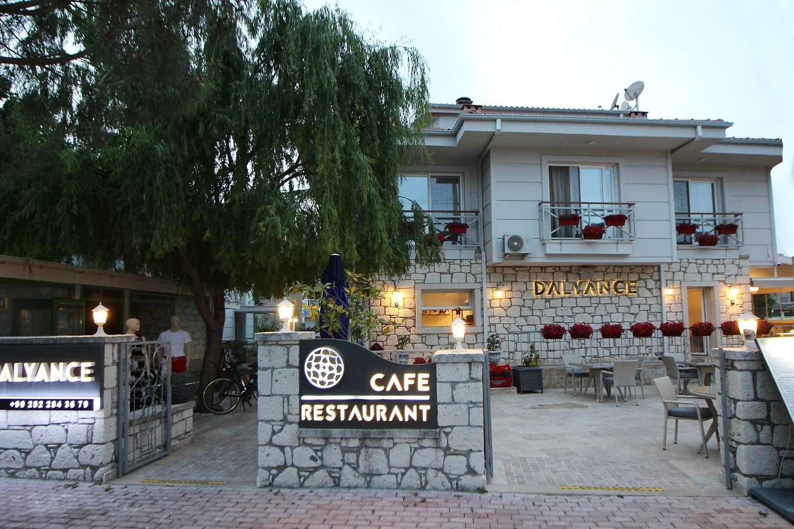 A cafe restaurant with a stone facade, outdoor seating, and a sign indicating it is part of the Daliance hotel.