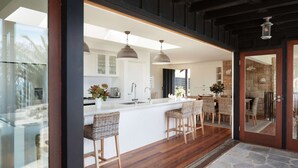 A modern kitchen with a central island, bar stools, and pendant lighting. - Northview Villa by Contemporary Hotels (PALM BEACH)