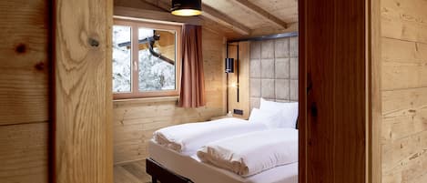 Dormitorio de cabaña de madera con cama, ventana y luz de techo.