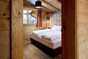 A wooden cabin bedroom with a bed, a window, and a ceiling light.