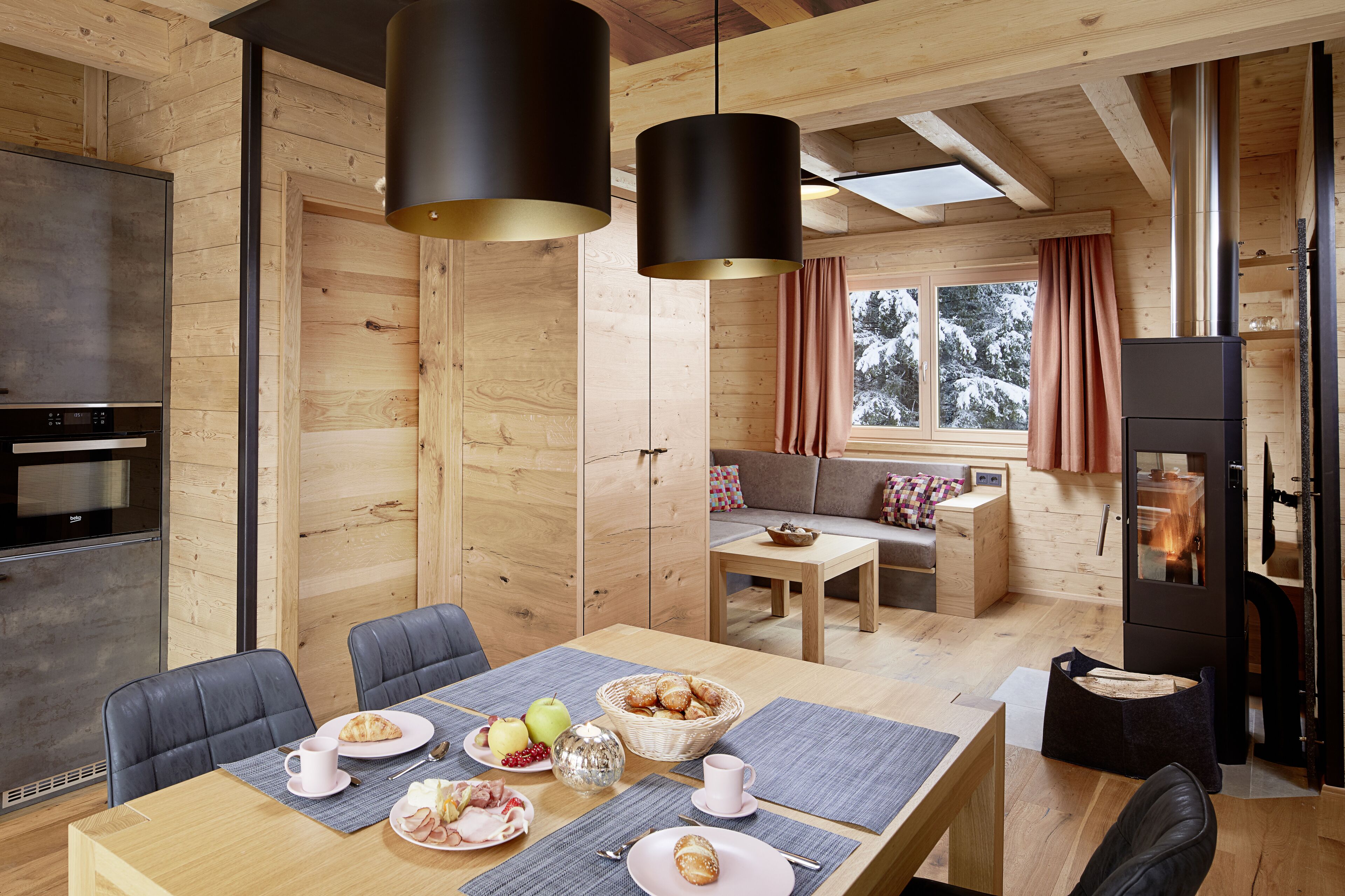 A cozy cabin interior with a dining area, a sofa, and a fireplace.