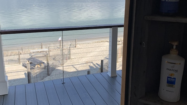 A balcony with a view of the beach and the sea.