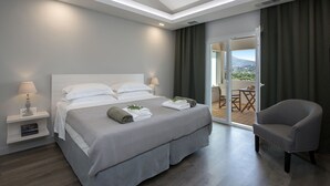 A modern hotel room with a large bed, a sitting area, and a balcony with a view. - Gem Villa in Viros Corfu  (Corfu)