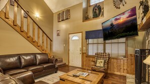 A living room with a brown leather sofa, a wooden coffee table, and a staircase.