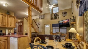A spacious kitchen with wooden cabinets, a dining table set with wine glasses, and a cozy seating area with a leather couch.