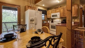 A kitchen with wooden cabinets, a refrigerator, microwave, and a dining table set with plates and glasses.