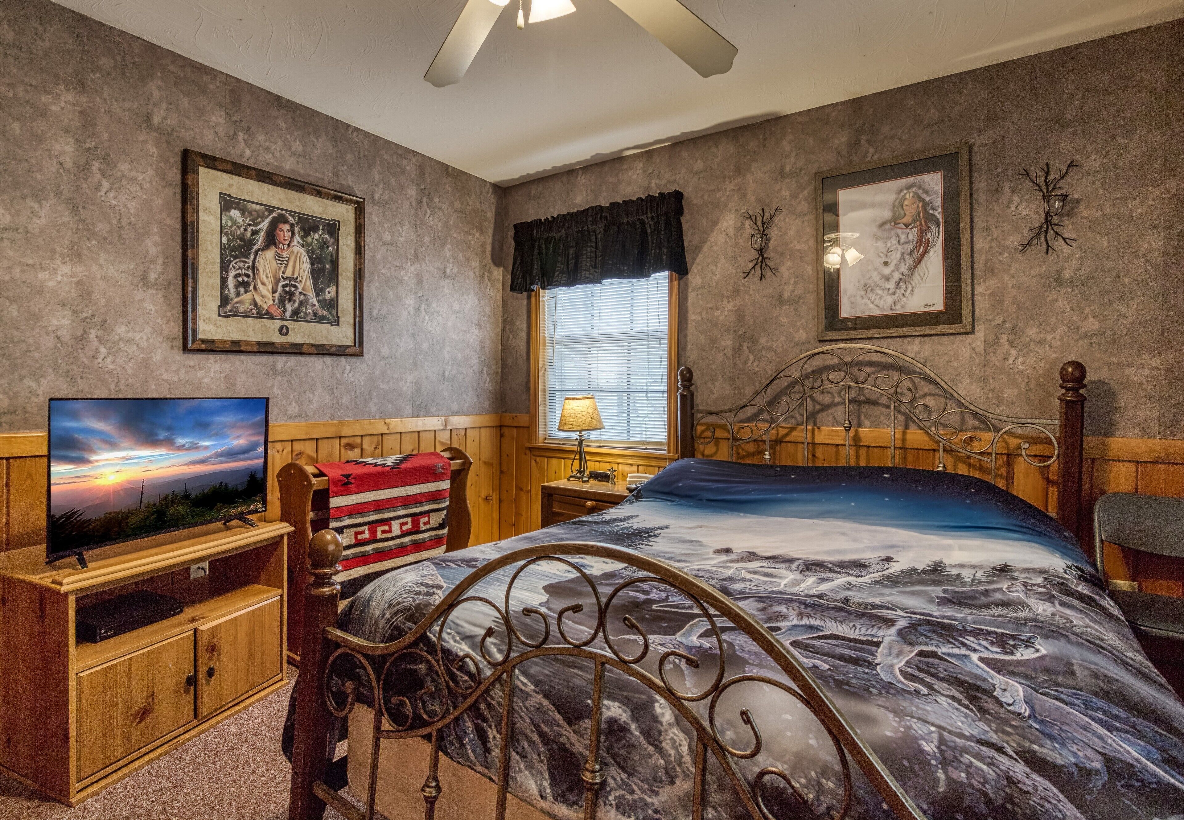 Ein Schlafzimmer mit einem Bett, einem Fernseher, einer Lampe und gerahmten Bildern an den Wänden.