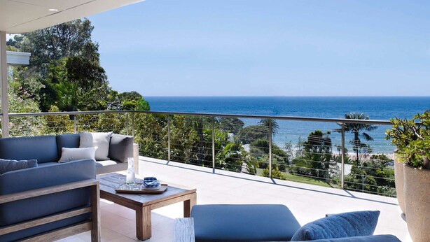 Un balcon avec un canapé, une table basse et une vue sur l’océan.