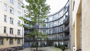 A courtyard with a tree, bicycles, and a building with balconies. - 2ndhomes Kluuvi Apartments 2 (Helsinki)