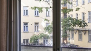 A view through a window of a building with multiple windows and balconies, trees, and bicycles outside. - 2ndhomes Kluuvi Apartments 2 (Helsinki)