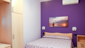 A bedroom with a bed, wooden wardrobe, and a wall-mounted air conditioner. - Beachfront apartment in Residence Rosa Virginia Pool (Gallipoli)