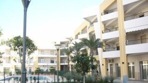 A multi-story hotel with balconies, a well-maintained lawn, and a street lamp. - Beachfront apartment in Residence Rosa Virginia Pool (Gallipoli)