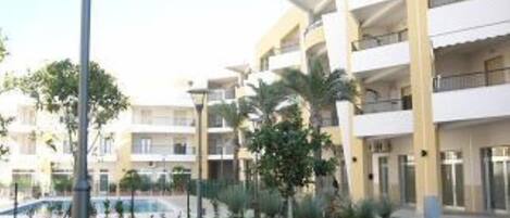 A multi-story hotel with balconies, a well-maintained lawn, and a street lamp.