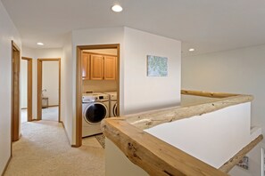 Una sala de lavandería con armarios de madera y una lavadora.