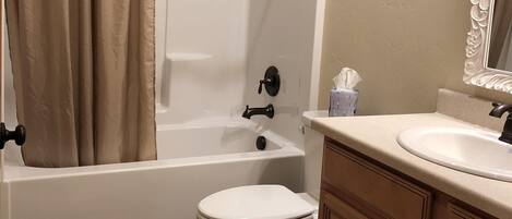 Un baño con bañera, inodoro y tocador.