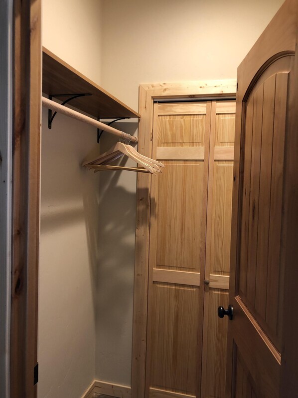 A wooden closet with a hanging rod and a door.