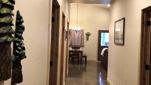 A hallway with a polished concrete floor, wooden doors, and a chandelier.