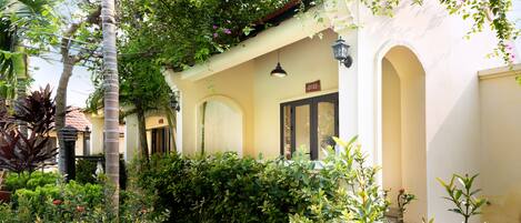 A building with a covered porch, a door with a sign above it, and a small archway.