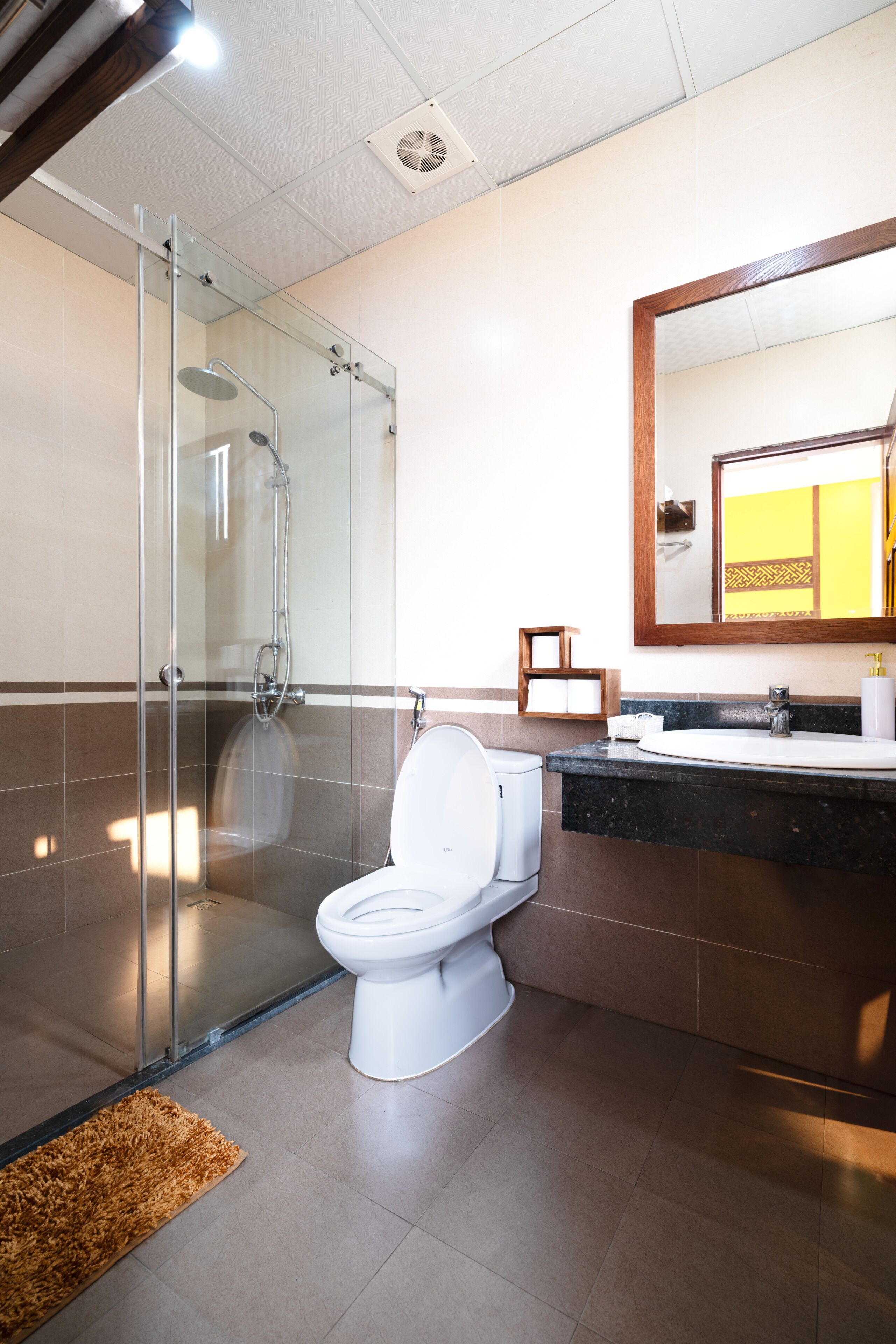 A modern bathroom with a glass-enclosed shower, a white toilet, and a sink with a mirror above it.