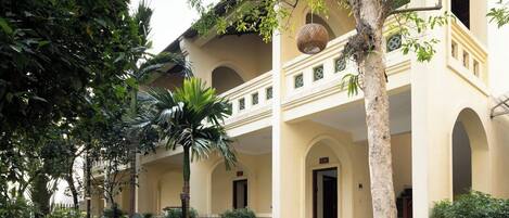 A building with a courtyard, a palm tree, and a staircase leading to an entrance.