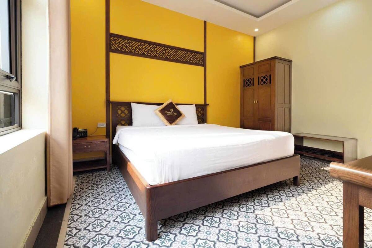 Quarto de hotel com uma cama, um guarda-roupa e uma mesa de cabeceira.