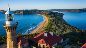 A coastal view with a lighthouse, beach, and forested area. - Pacific Blue by Contemporary Hotels (PALM BEACH)