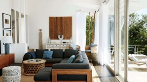 A modern living room with a sectional sofa, a coffee table, and a decorative wall piece. - Pacific Blue by Contemporary Hotels (PALM BEACH)