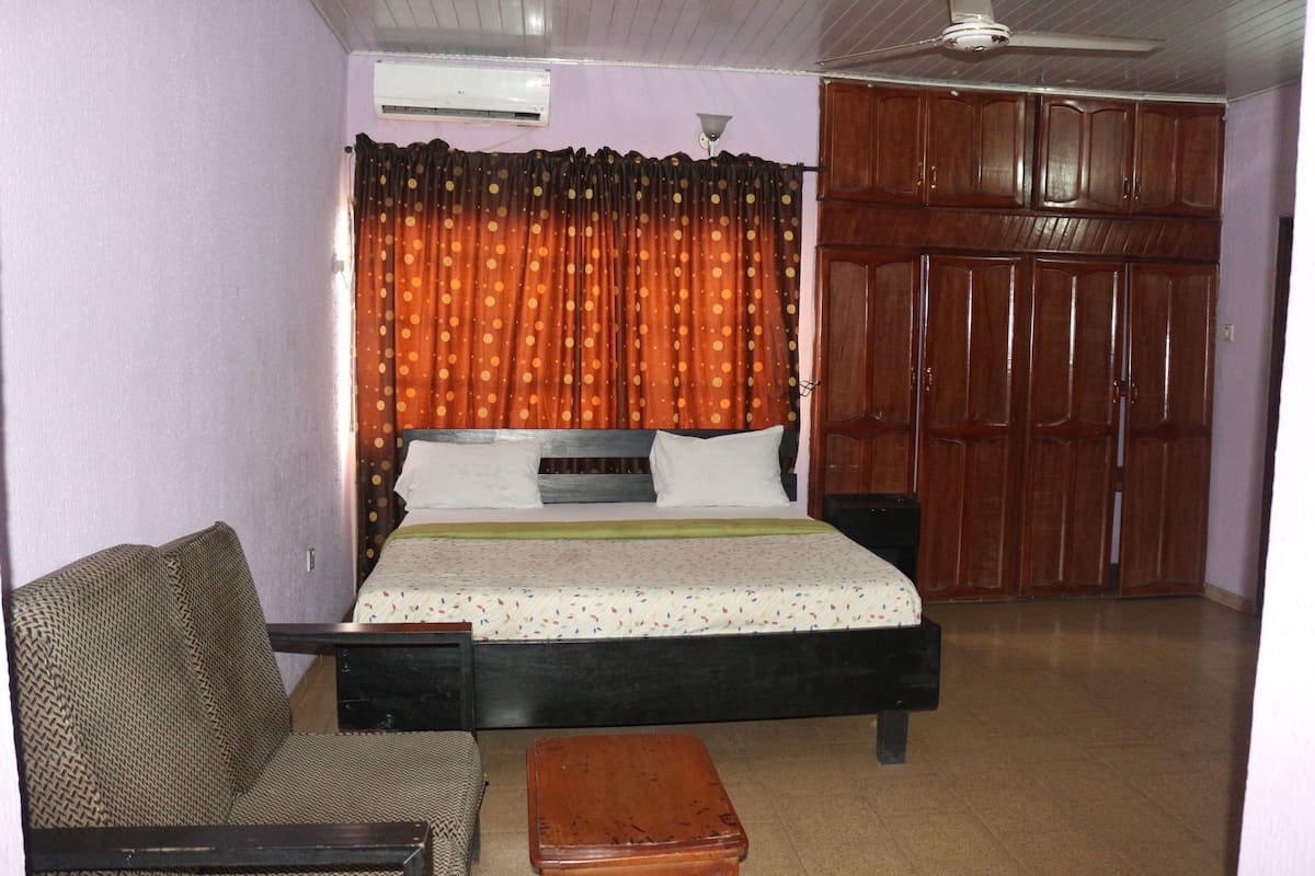 Un dormitorio con una cama, un armario de madera, un sofá y un ventilador de techo.