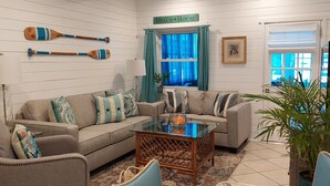 A living room with a sofa, armchairs, a glass coffee table, and decorative items like wooden paddles. - VINTAGE BEACH COTTAGE
BOOK NOW! SAVE!!
90 sec. walk to beach!
Supplies Included! (North Myrtle Beach)