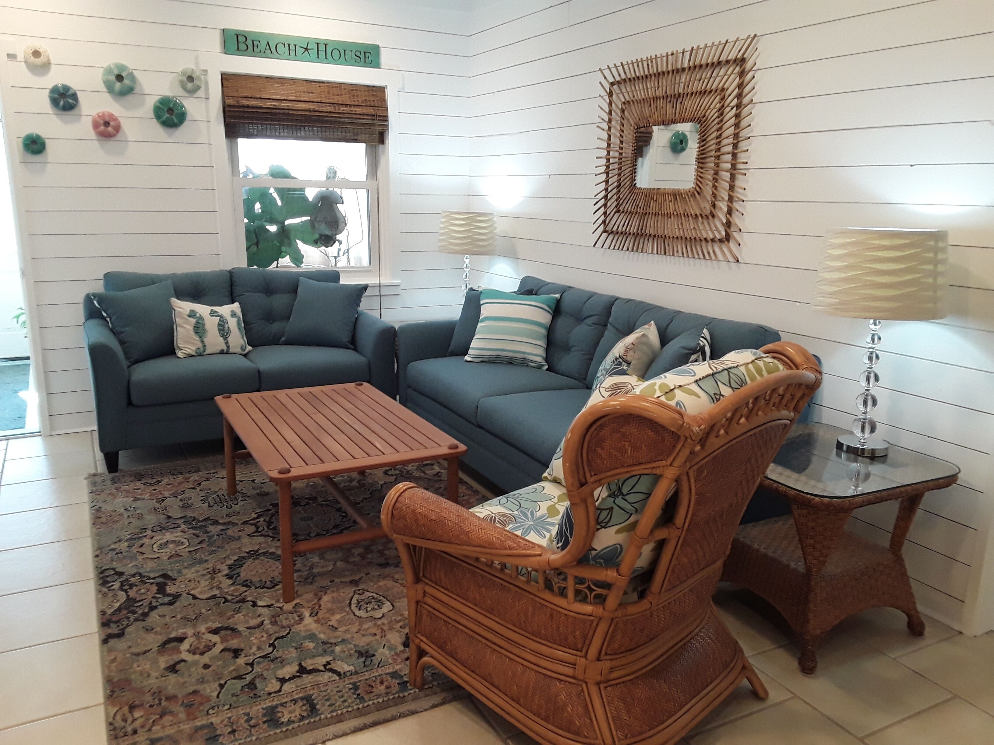 A cozy living room with a sectional sofa, a wooden coffee table, a wicker armchair, and a small side table.