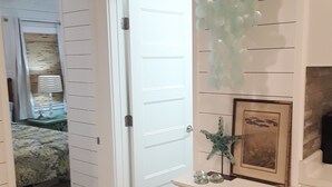 A hallway with a white door, a bed with a floral bedspread, and a dresser with drawers and a mirror. - VINTAGE BEACH COTTAGE
BOOK NOW! SAVE!!
90 sec. walk to beach!
Supplies Included! (North Myrtle Beach)