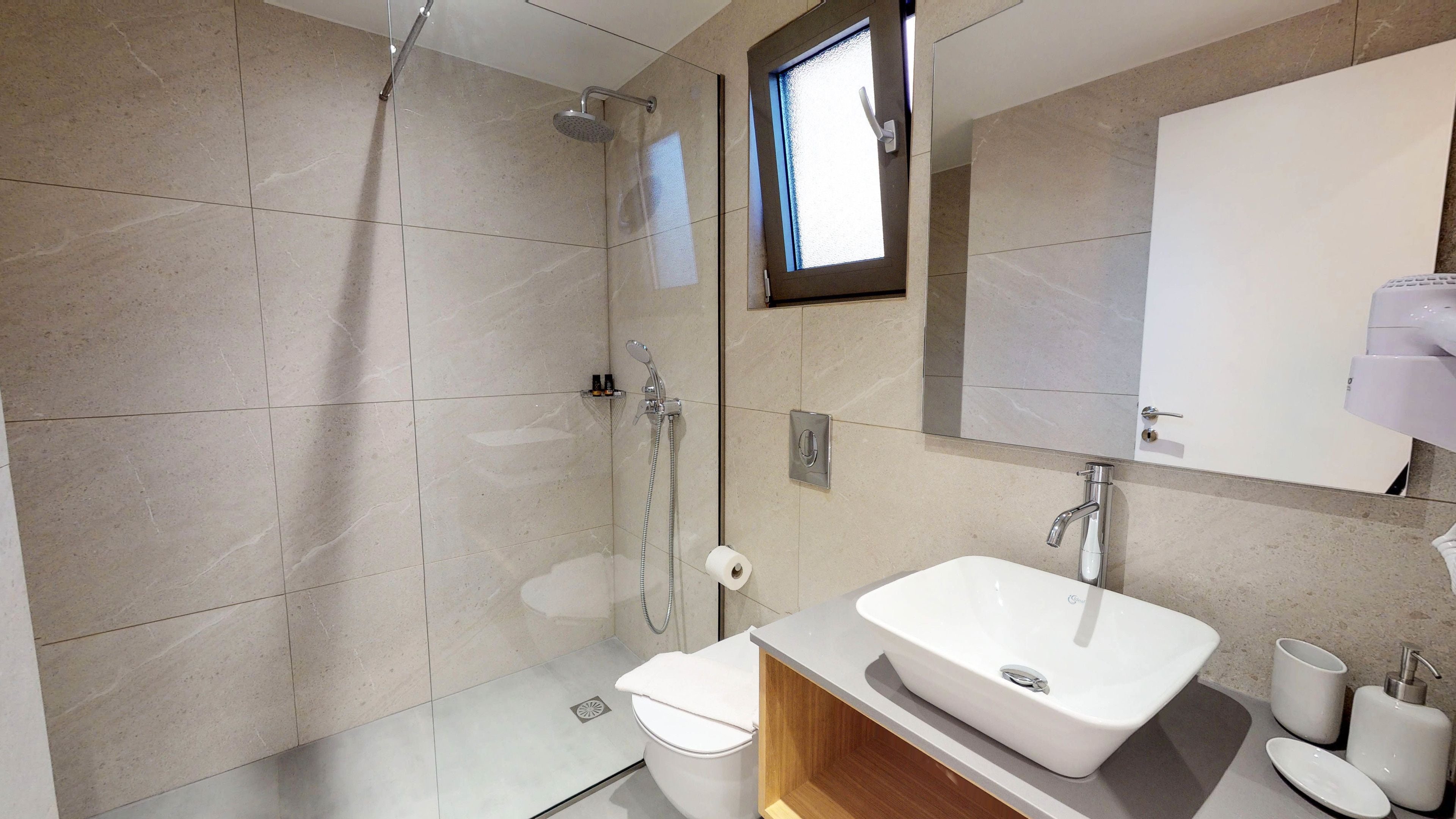 A modern bathroom with a shower, toilet, and sink.