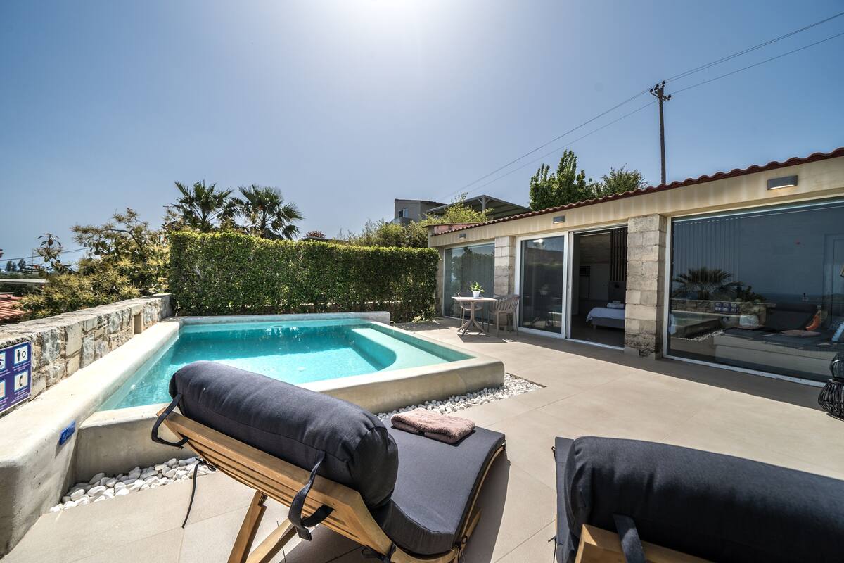 A modern outdoor pool area with lounge chairs and a glass-enclosed patio.