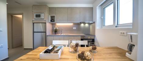 Una cocina moderna con una mesa de madera, recipientes de vidrio con objetos decorativos y electrodomésticos de acero inoxidable.
