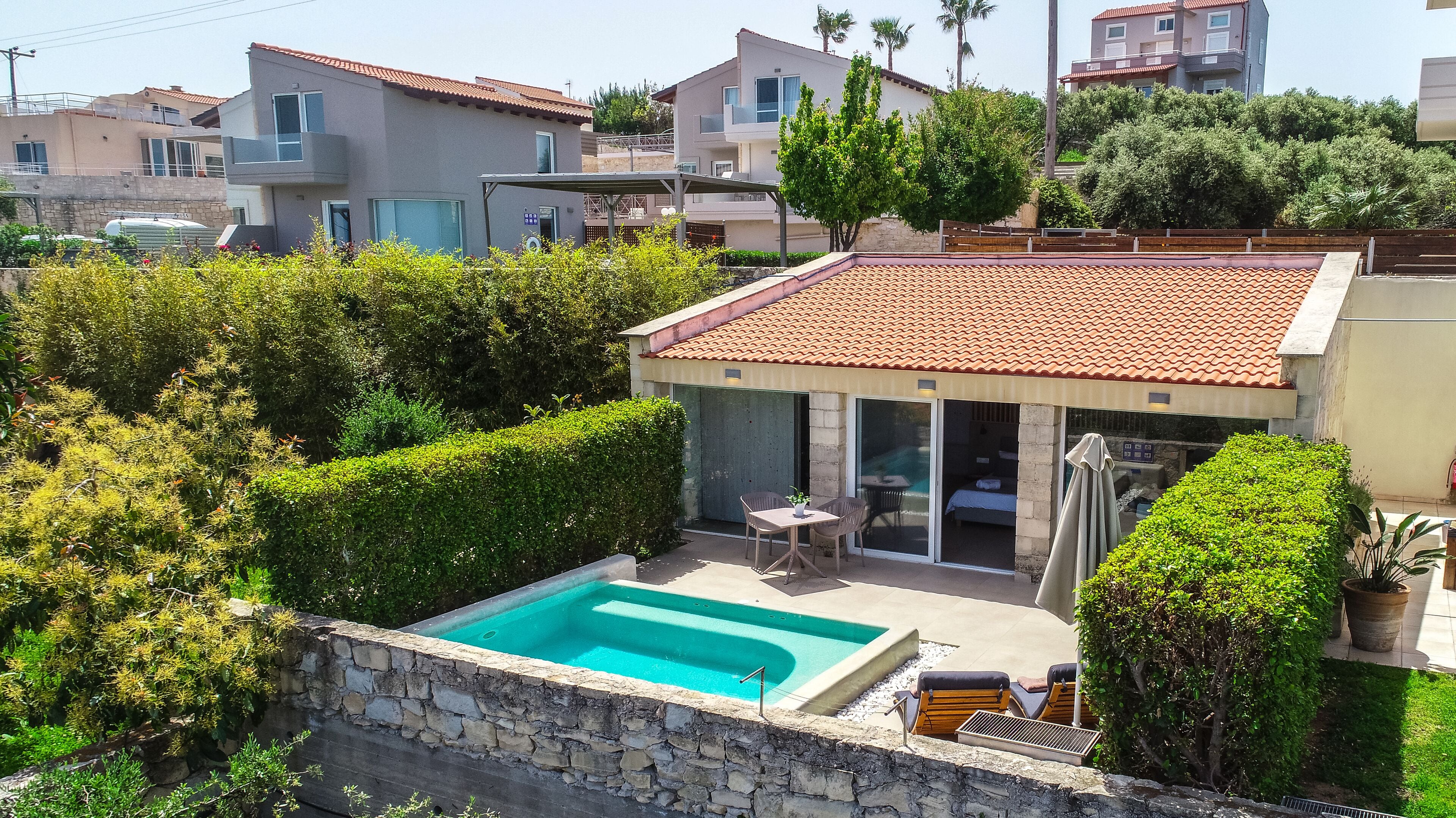 A residential property with a swimming pool, outdoor seating, and a covered patio area.