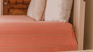 Ein Bett mit gemustertem Überwurf, eine Holztür und ein weißes Kopfende.