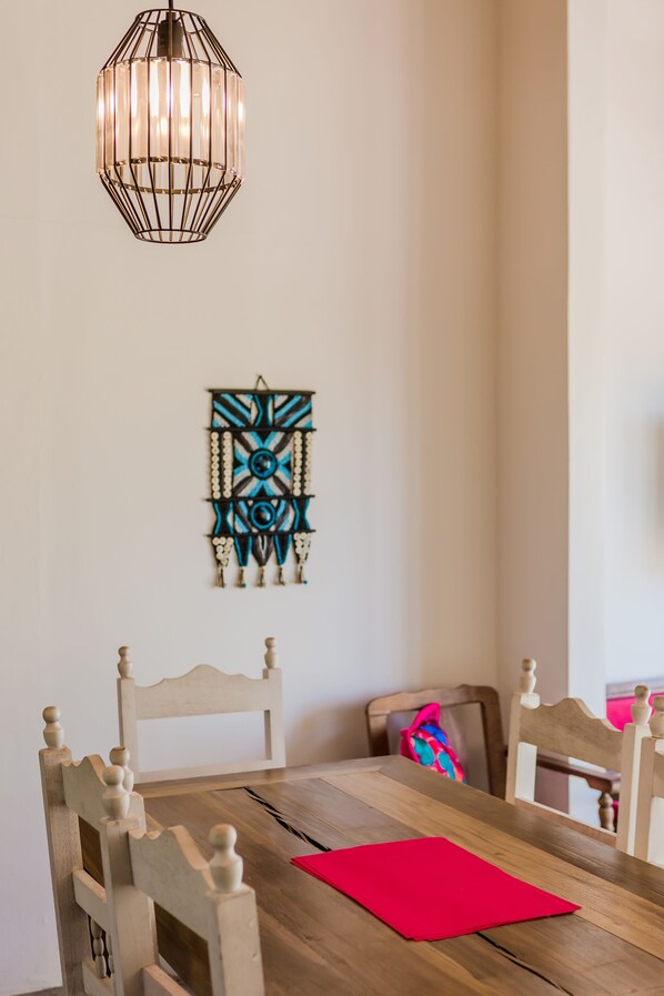 A dining area with a wooden table, chairs, a hanging light fixture, and a wall decoration. - Best view condo with sunny terrace (San Pedro)